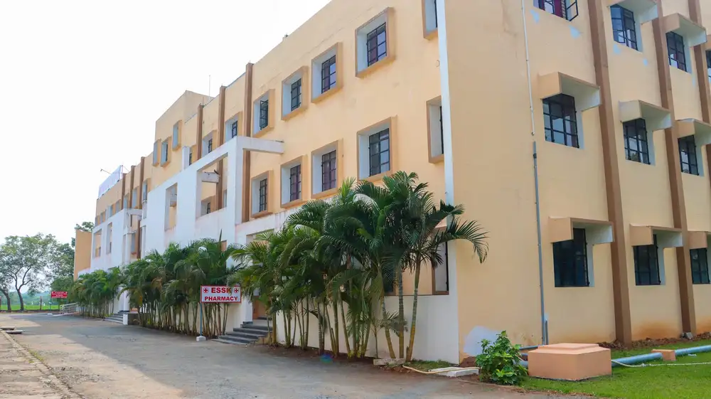 The side of the college building, lined with palm trees, with an ESSK Pharmacy sign at the entrance
